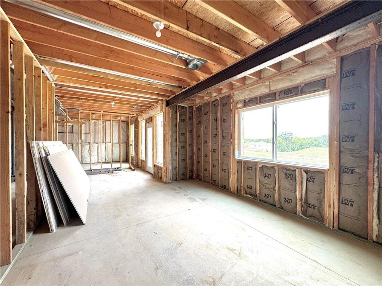 Insulated exterior walls, a steel beam, and open floor framing in a home under construction